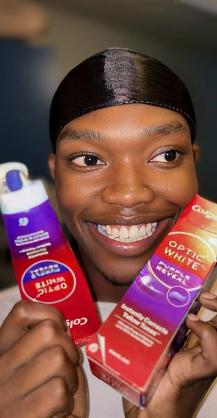 Creator holding Colgate Optic White toothpaste and whitening products
