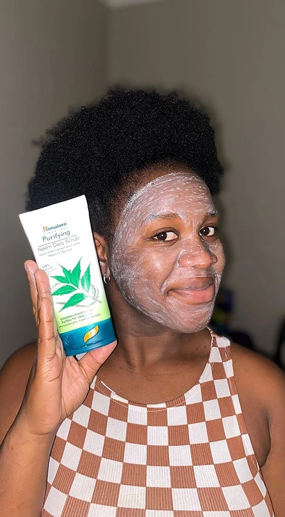 Woman holding Himalaya Purifying Neem facial scrub after applying it
